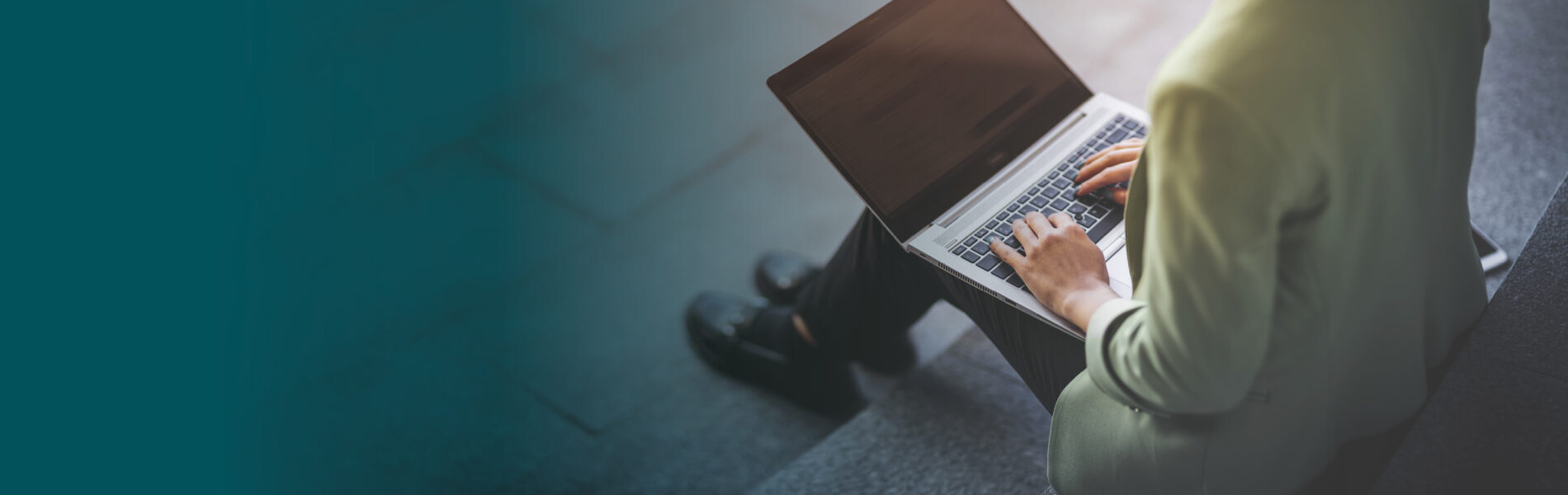 Woman sitting on steps outside working on a laptop