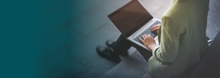 Woman sitting on steps outside working on a laptop