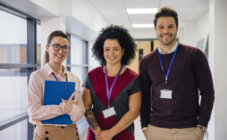 Three teachers standing in a hallway smiling