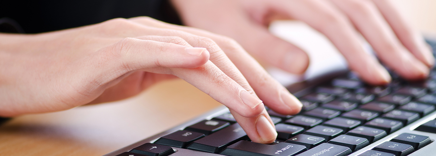 Closeup of hands typing on a computer keyboard