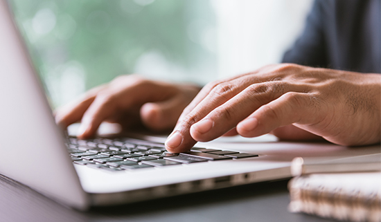 Image of close up of hands operating laptop