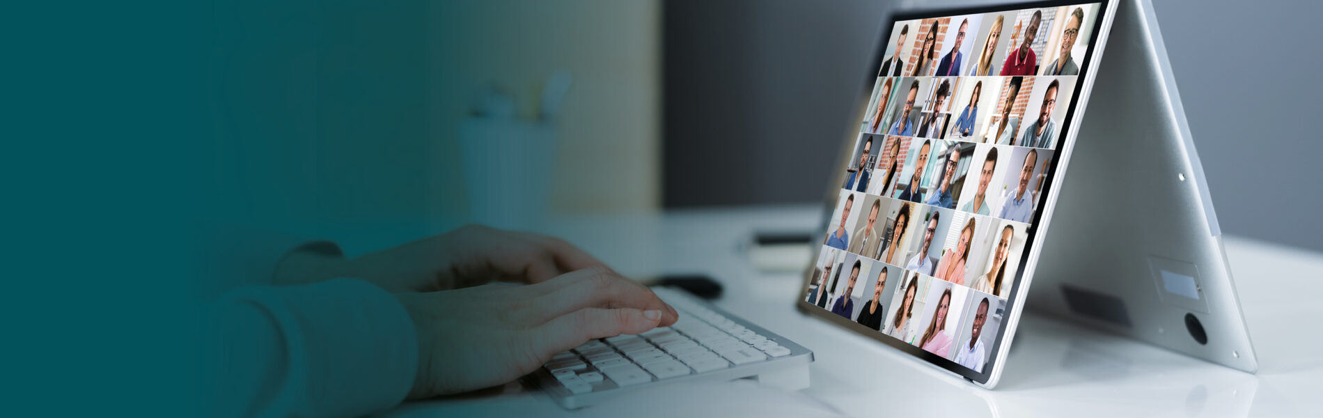 Close up of hands typing on keyboard whilst viewing Teams call on display monitor